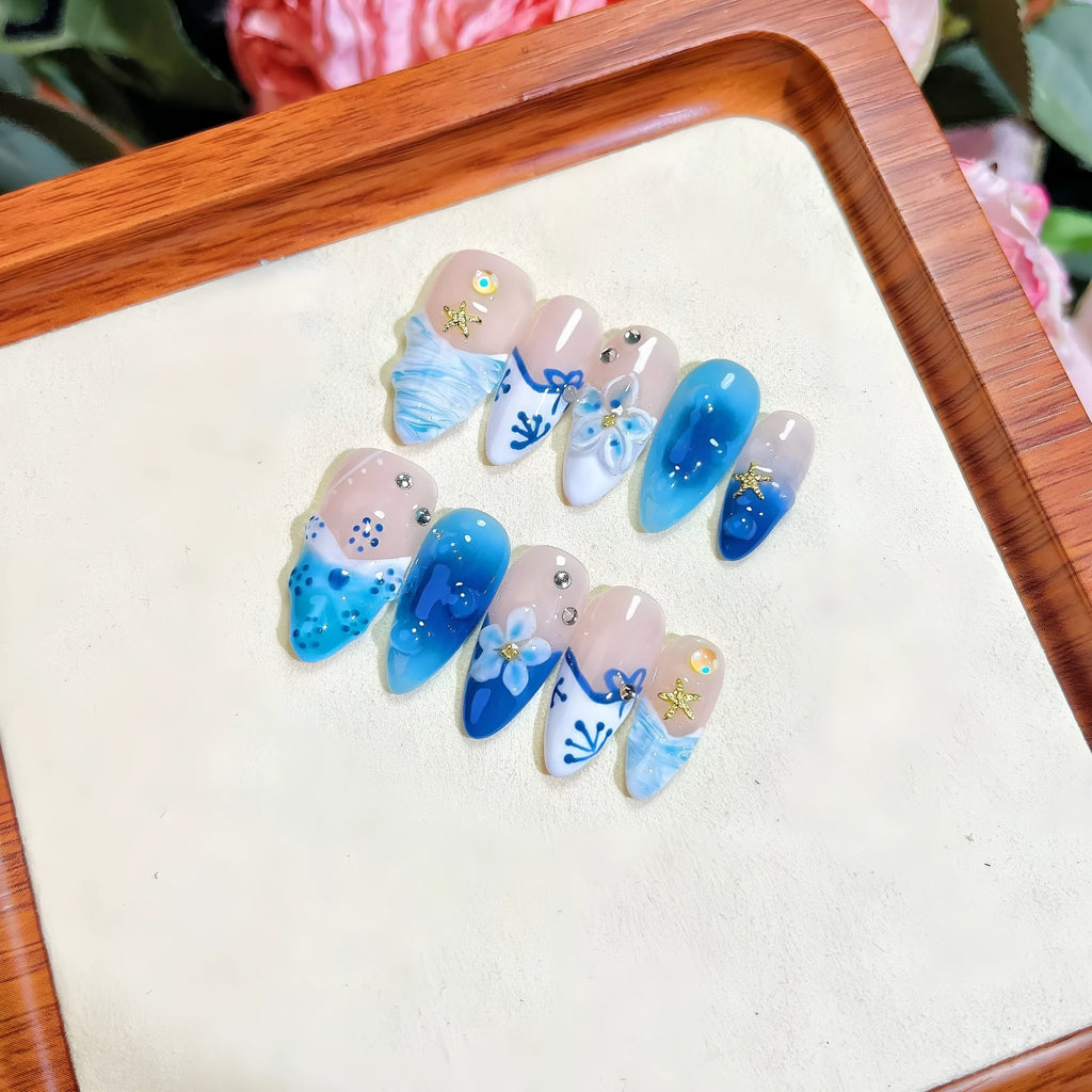 Set of blue hand-painted carved summer ice transparent plastic fake nails in XS, S, M, and L sizes.
