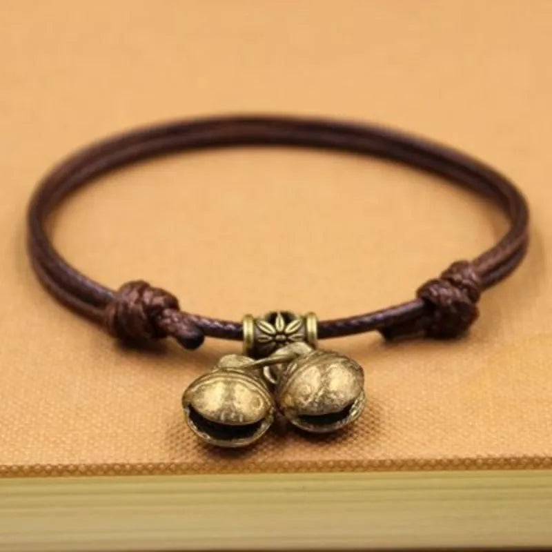 Black nylon rope dog collar with a small brass bell, shown adjusted on a model.