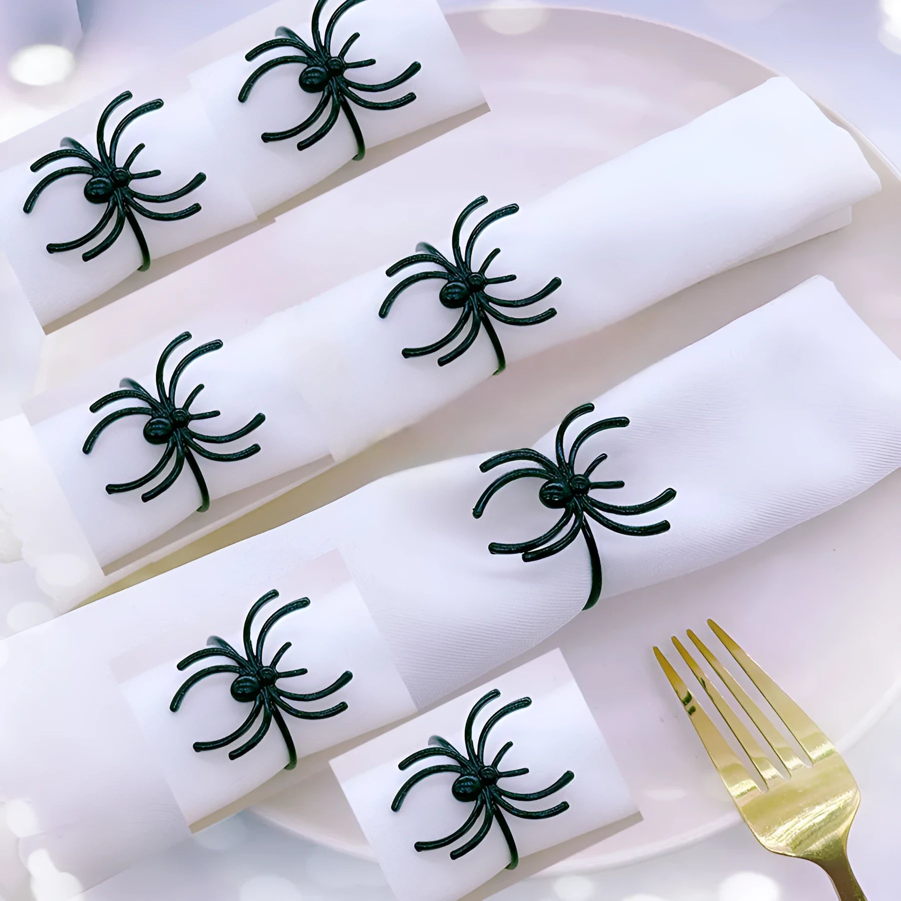 Set of six black metal spider-shaped napkin rings for Halloween table decoration.