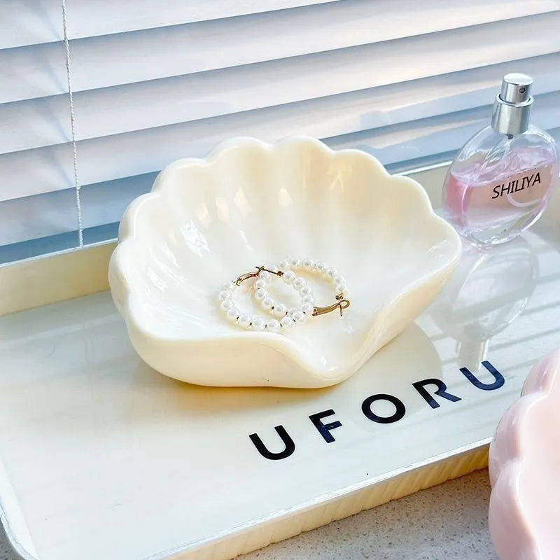 White shell-shaped plastic soap dish for bathroom countertop.
