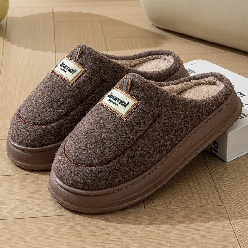 Men's grey suede slippers with a thickened sole on a wooden floor.