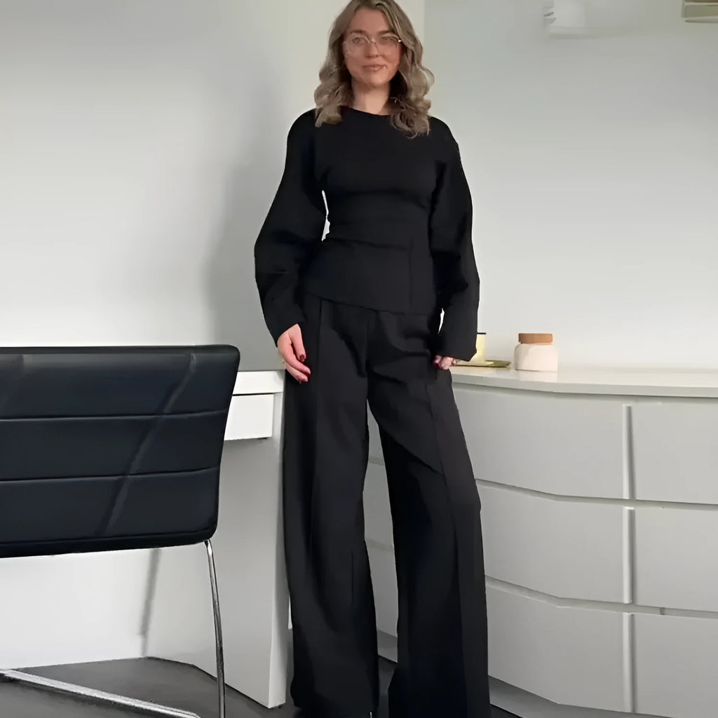 Women's black polar fleece suit set with long sleeve pleated top and wide leg trousers on a hanger.