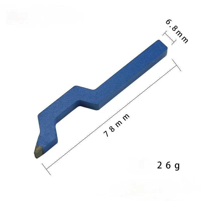 Gold-coloured curved character steel stamping tool for jewellery making on a workbench.