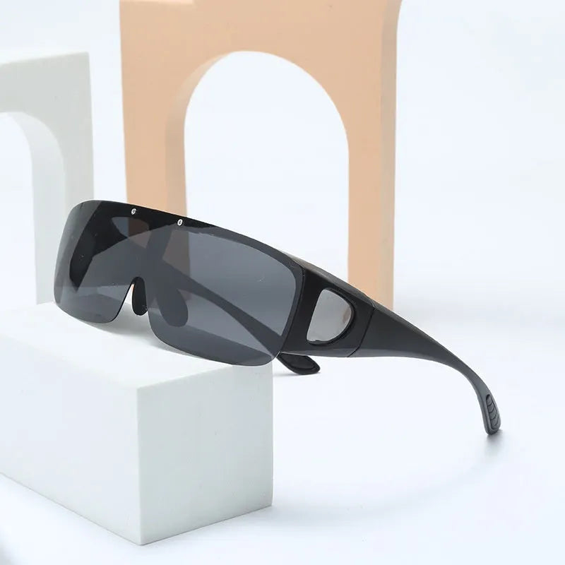One-piece polarised sunglasses with myopia correction and multiple interchangeable coloured lens sheets laid out.