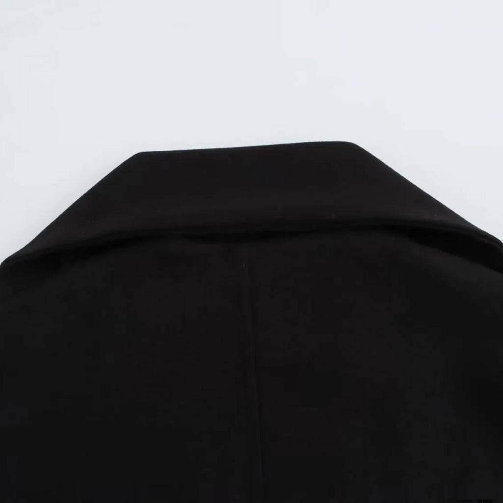 Women's long black overcoat with a grey fur collar and pockets, shown on a model.