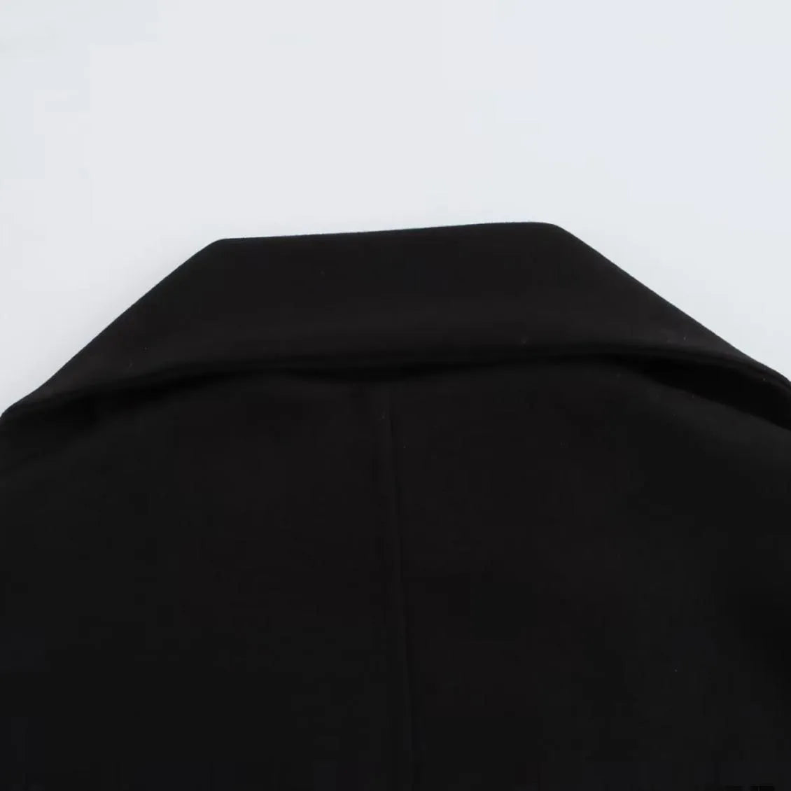 Women's long black overcoat with a grey fur collar and pockets, shown on a model.
