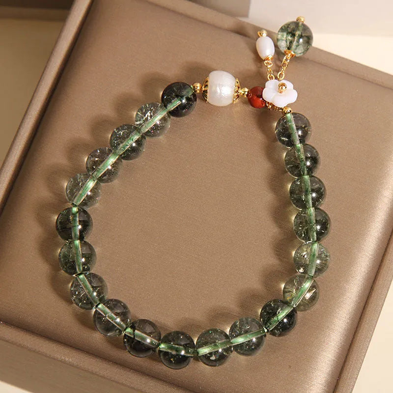 Green phantom quartz crystal bracelet with shell flower charm on a woman's wrist