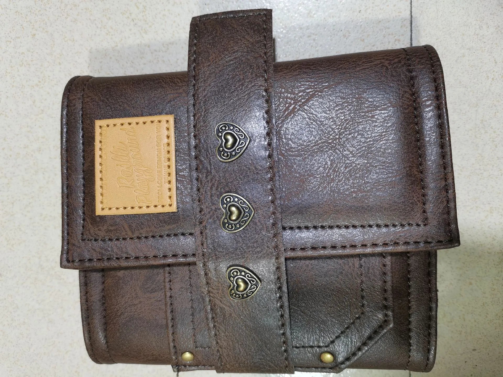 Brown A7 retro notebook with buckle closure showing loose-leaf binding and raw wood pulp paper