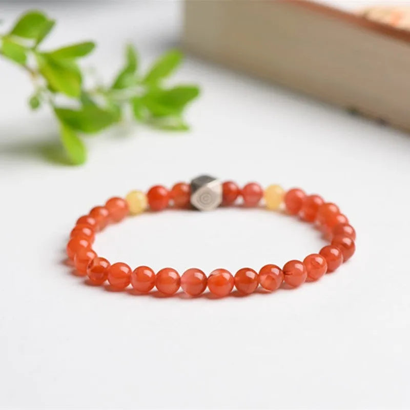 Natural red Nanhong Agate bracelet with a central amber beeswax bead on a white background.