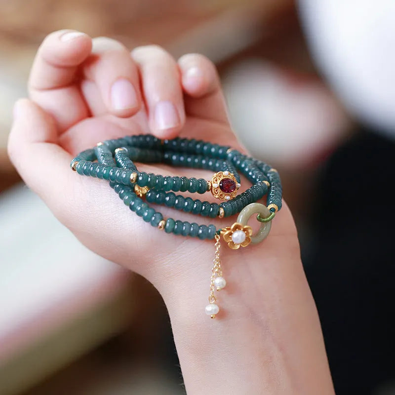 Close-up of a women's blue water jade abacus bead bracelet with three rings, tourmaline, and pearl accents.
