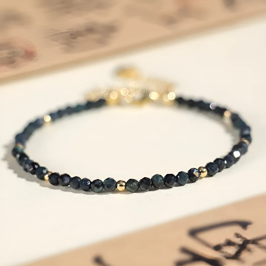 Close-up of a women's bracelet with 3mm blue tourmaline cut beads and silver-toned spacer beads on a wrist.