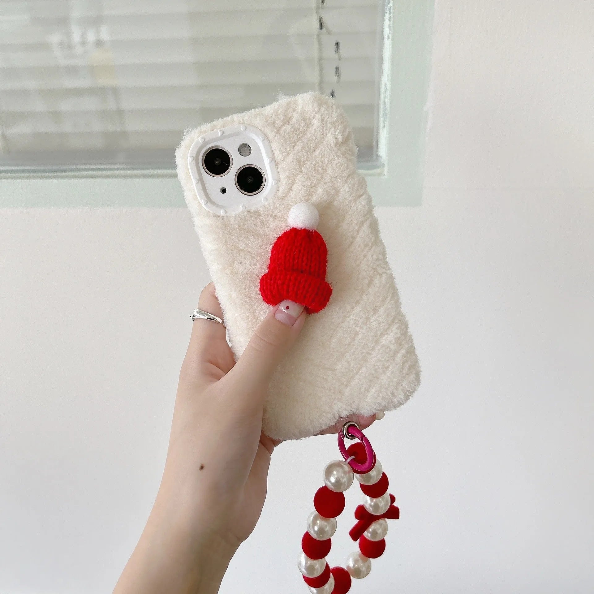Red silicone phone case with plush Christmas hat bracelet for iPhone on white background
