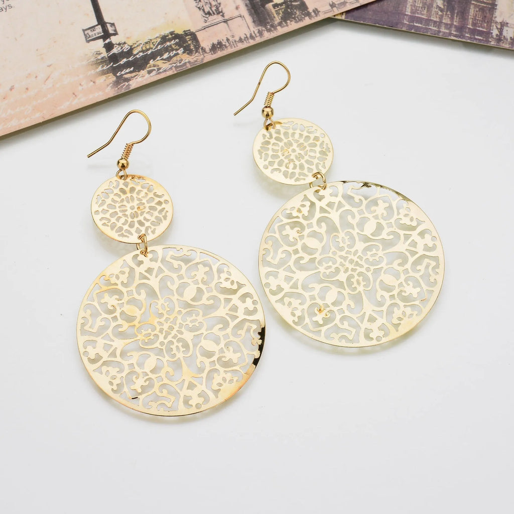 Women's round hollow gold drop earrings with dangle design on a light background