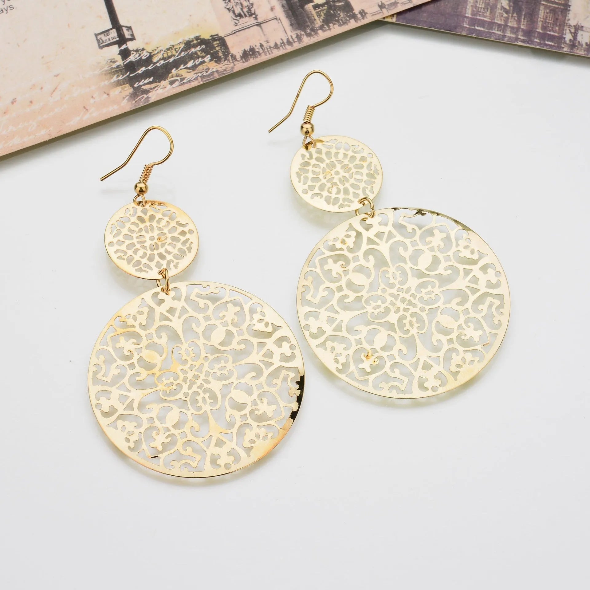 Women's round hollow gold drop earrings with dangle design on a light background