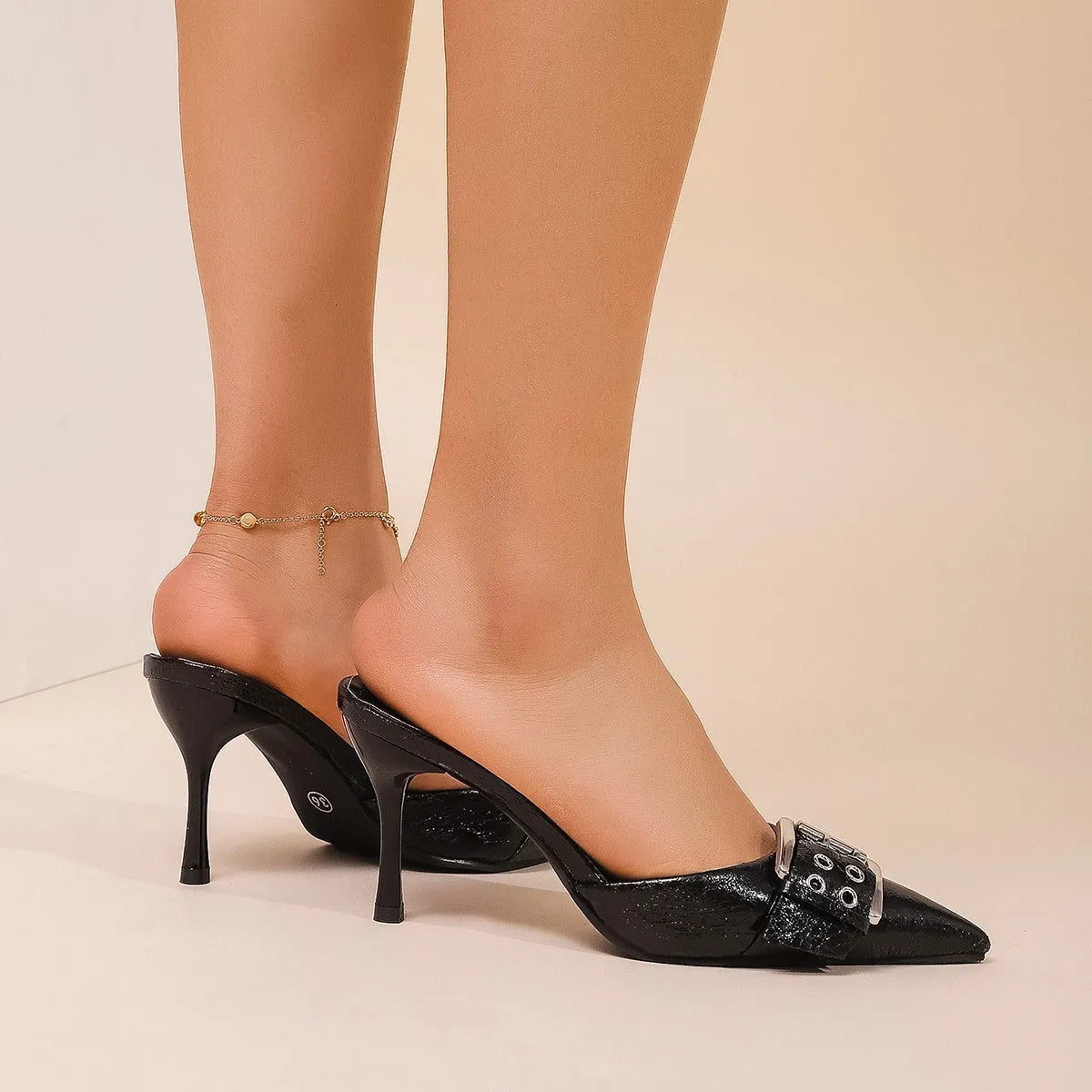 Black women's high heels with decorative buckle on ankle strap and pointed toe design