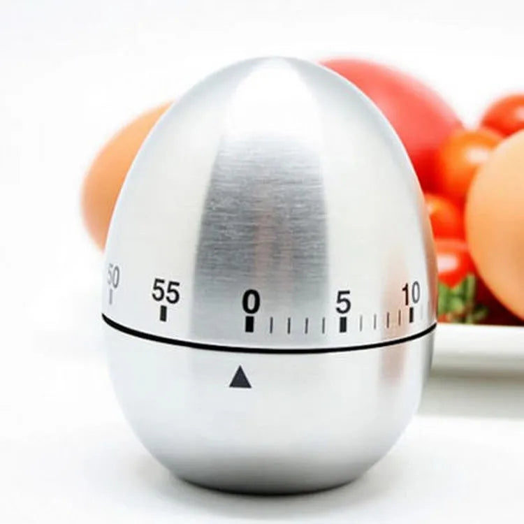 Stainless steel egg-shaped mechanical kitchen timer on a kitchen worktop.