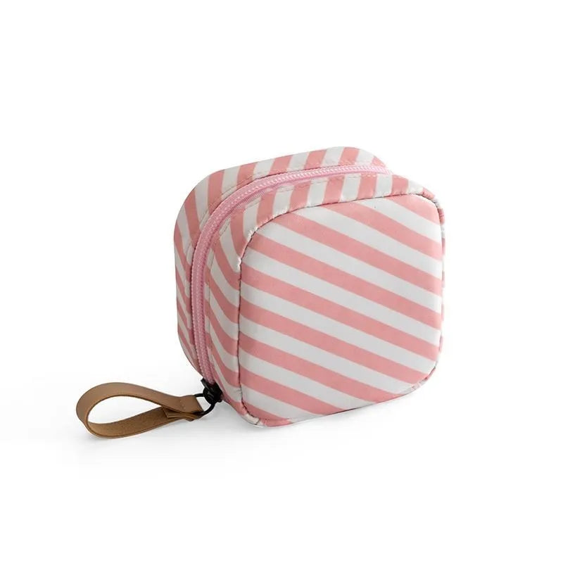 Blue cloth cube-shaped makeup storage bag on a table.