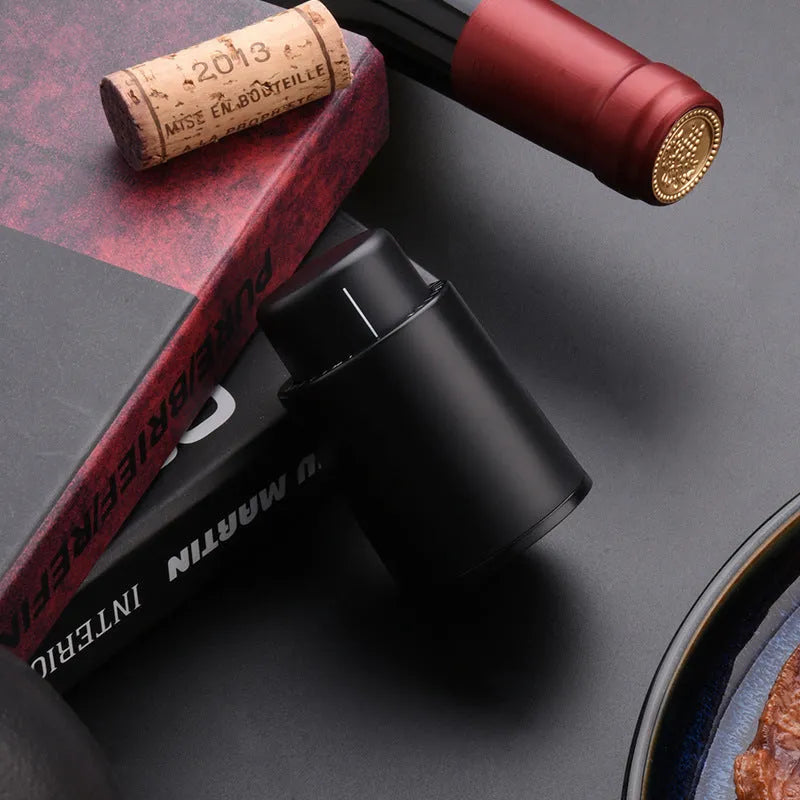 Automatic electric wine opener with black ABS shell and foil cutter set on a table alongside a wine bottle