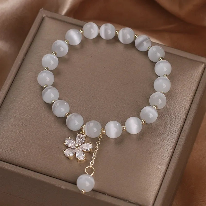 White cat's eye stone women's bracelet with a safety buckle and small flower tassel.