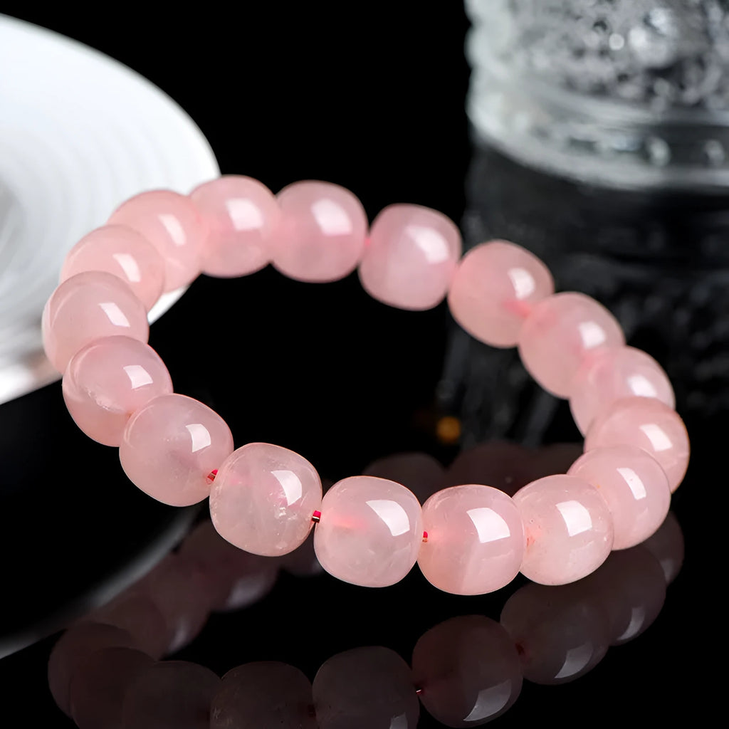 Close-up of a pink natural crystal barrel bead bracelet with geometric beads on a wrist.