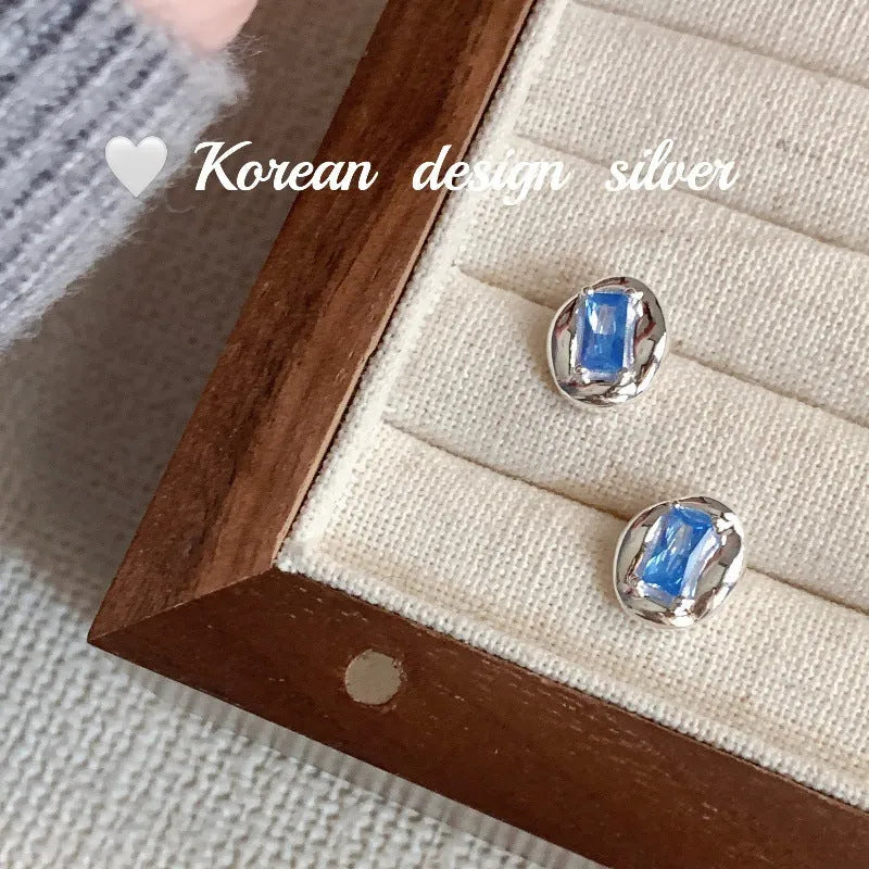 Sterling silver earrings with heart-wrapped oval blue diamond design and electroplated finish