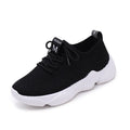 White thick-soled women's flyknit trainers with front strap and rubber sole.