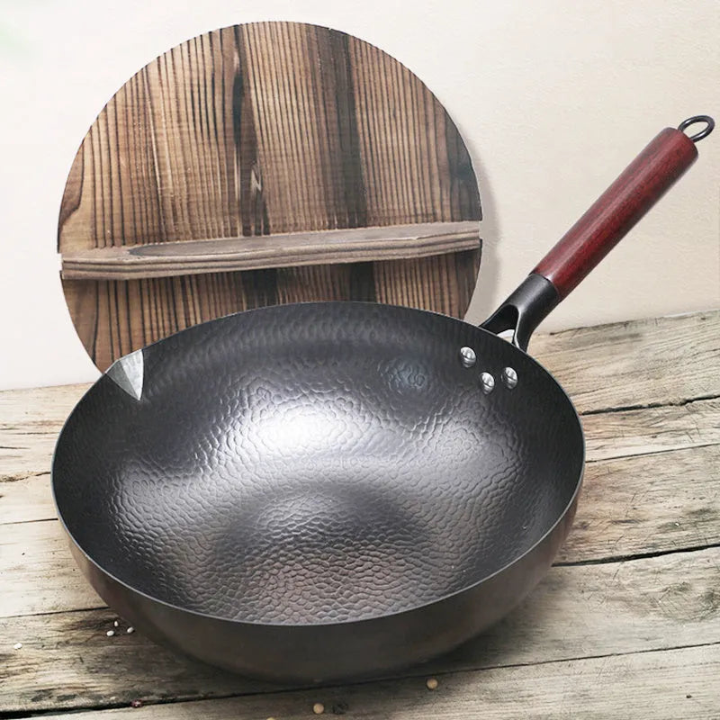 Handmade traditional black iron wok with a wooden handle, shown with a glass lid.