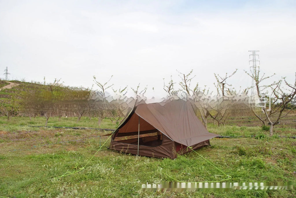 Brown ultralight A-frame hiking tent pitched with hiking poles in an outdoor setting