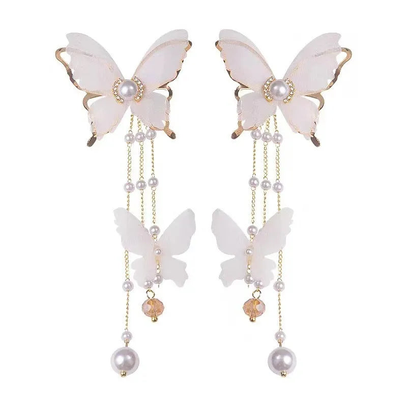 A pair of white butterfly-shaped earrings with tassel lace, pearls, and clear rhinestones on a copper alloy base.