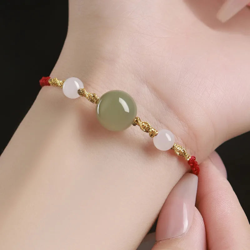 Hand-woven red rope bracelet with Hetian jade beads and a detailed zodiac charm pendant.
