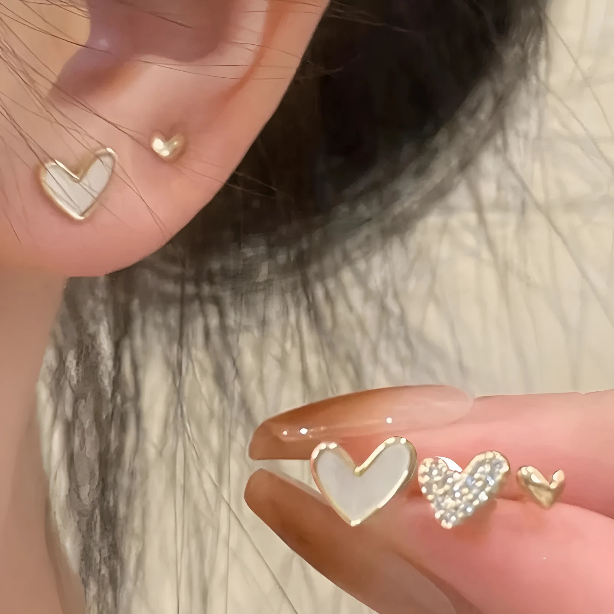 Three pairs of women's heart-shaped alloy earrings in gold, black, black and white, and pink colours
