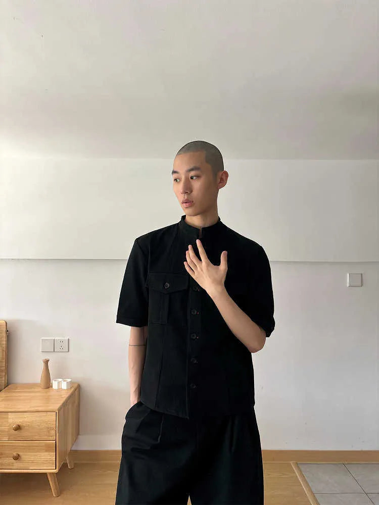 Black handmade loose-fit half sleeve hunting shirt with a shirt collar on a hanger.