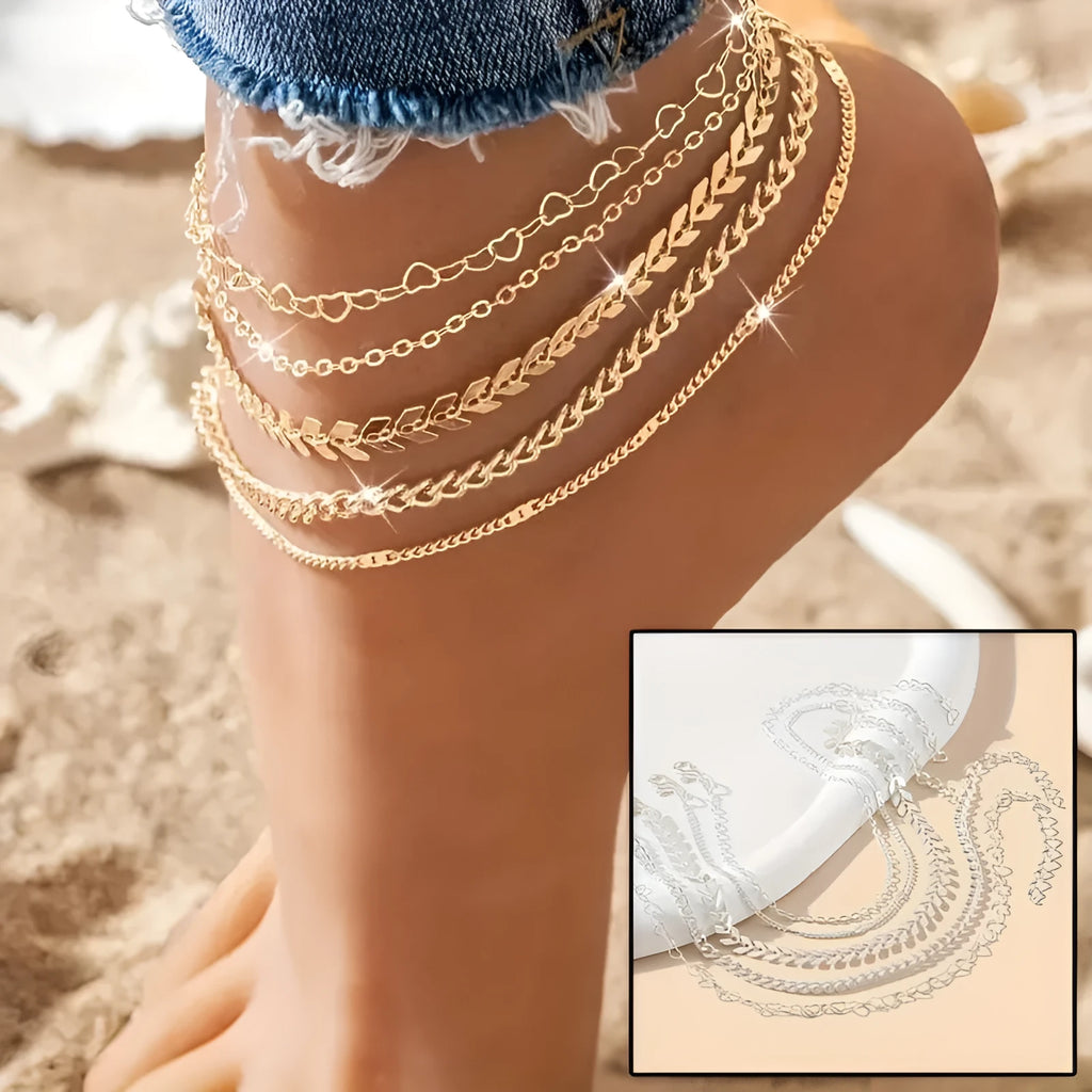 Five bohemian anklets with airplane chains and heart-shaped details in gold and silver on a white background