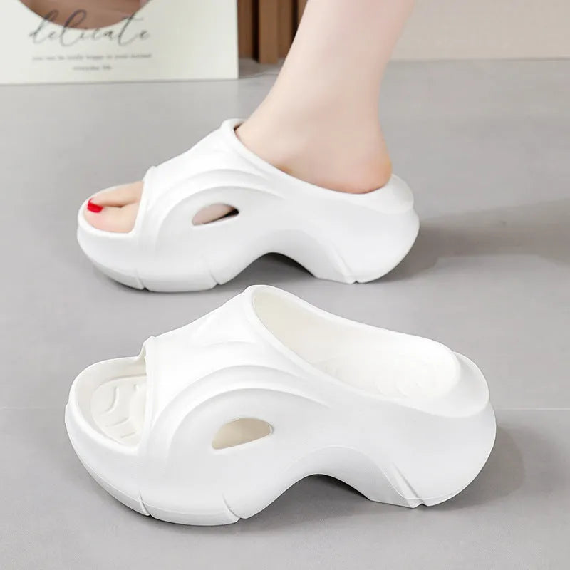Women's white thick-soled EVA slippers with round toe on a beach background.