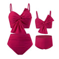 Women's orange nylon bikini set with large white bow print, showing top and swim trunks.