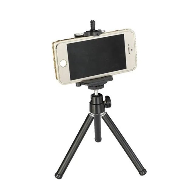 Compact mini desktop tripod with extendable aluminium legs and a black U-shaped phone clip attached.