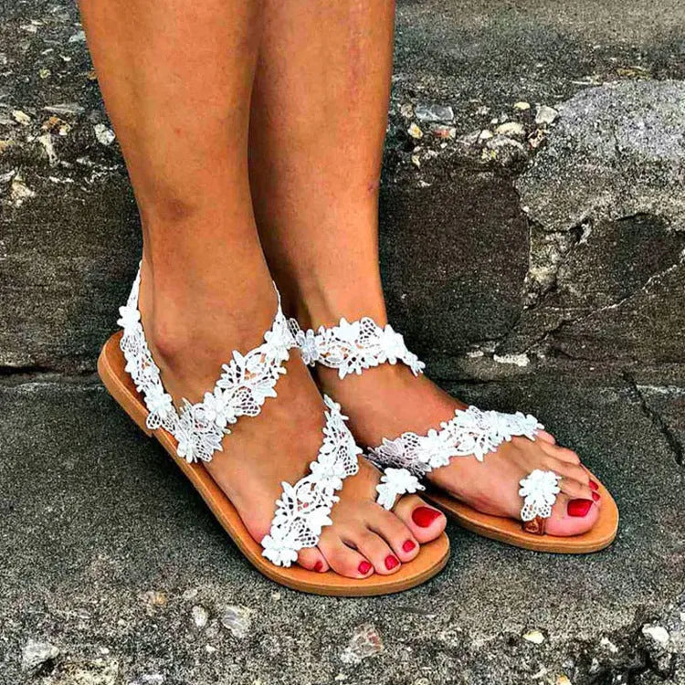 White women's sandals with rhinestone floral decoration on PU upper, slip-on flat design.