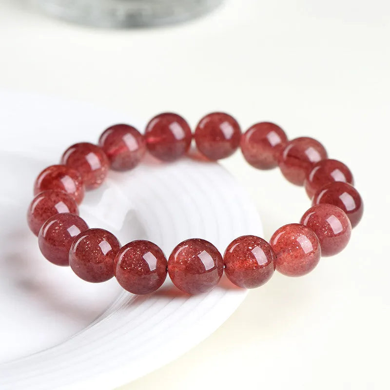 A stretch bracelet with round, pink strawberry quartz beads on an elasticated cord, shown in different size options.