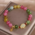 Women's bracelet with colourful tourmaline gourd blessing charm and floral clasp on a mixed material chain.