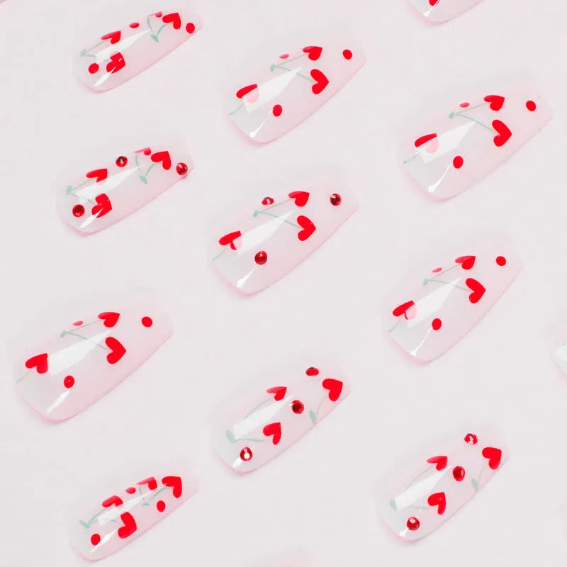 Red diamond and small cherry pattern nail art stickers on a sheet, with a tube of glue.
