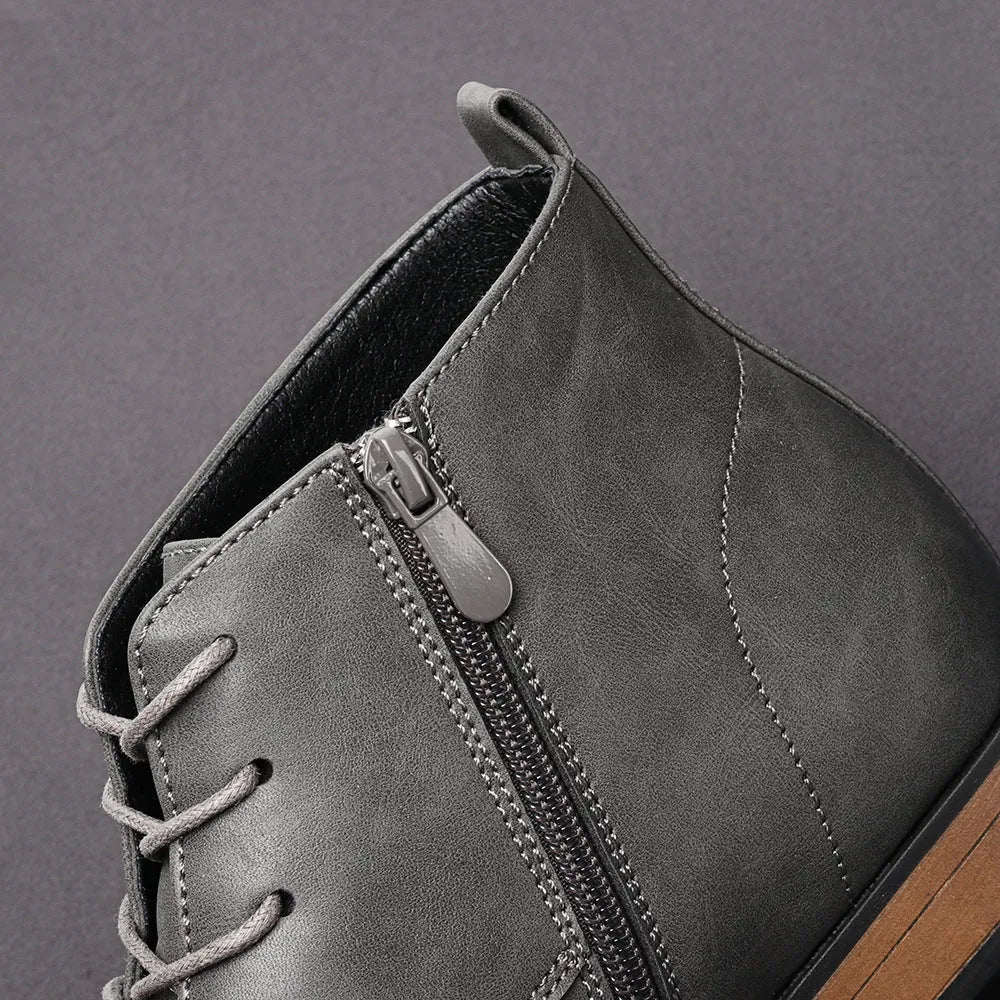 Men's black Chelsea boots with a side zipper, round toe, and low heel on a wooden sole.