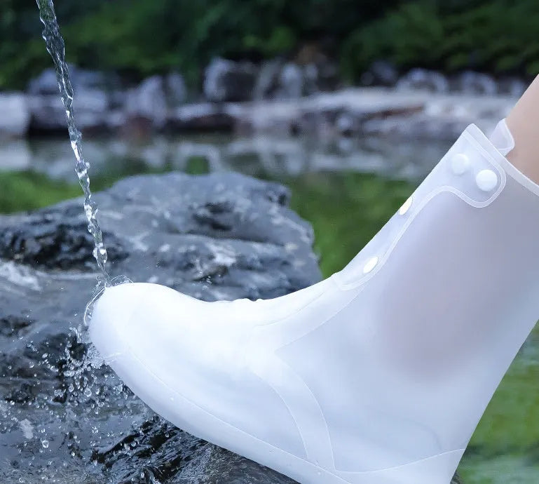 White high-top PVC reusable shoe covers for women on a rainy day background.