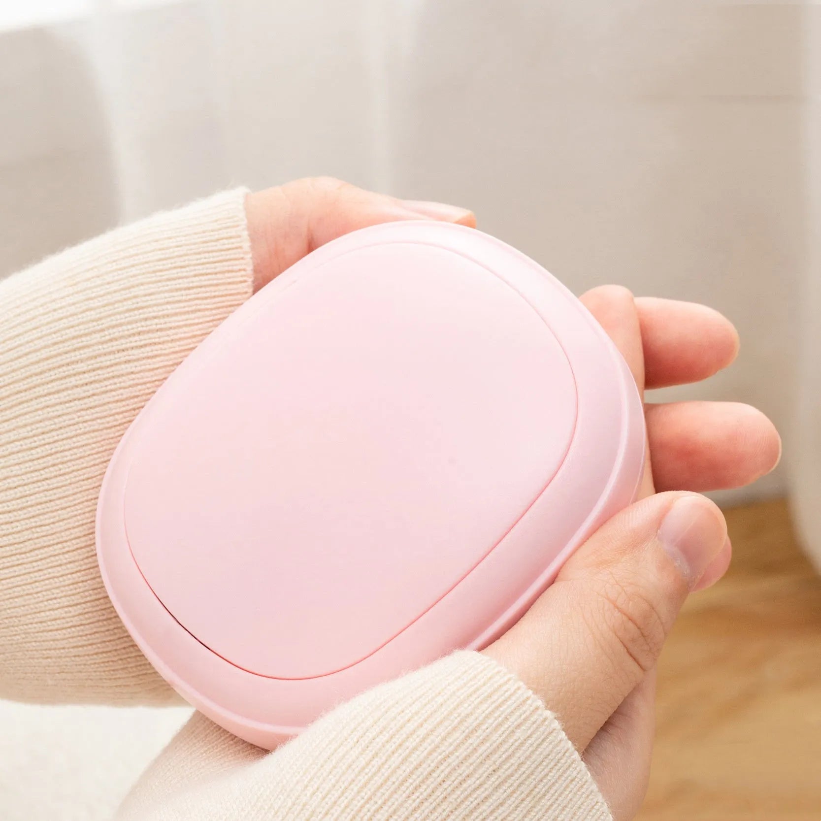 USB hand warmer in pink with three-gear temperature control and compact pebble design
