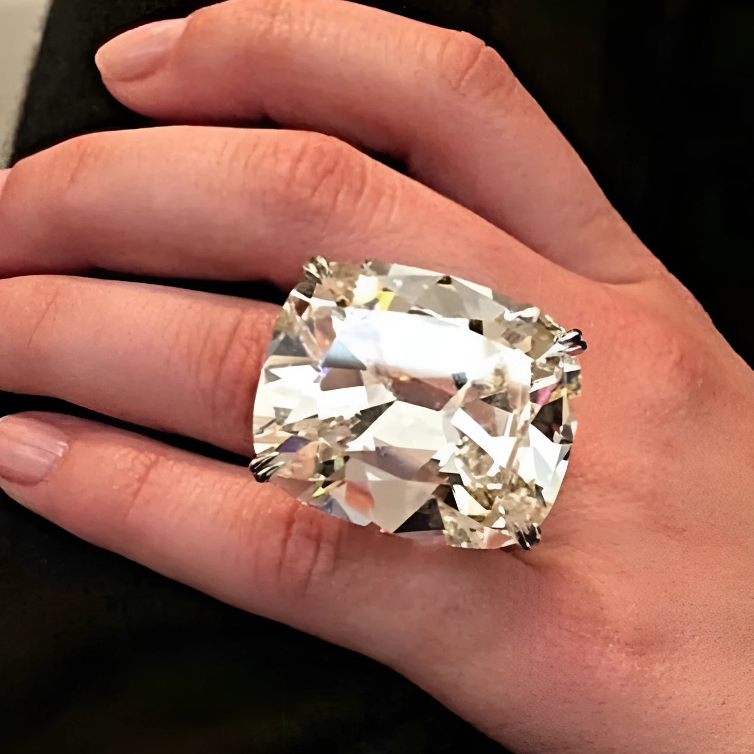 Women's white gold colour ring with a simple inlaid square diamond geometric design on a finger.