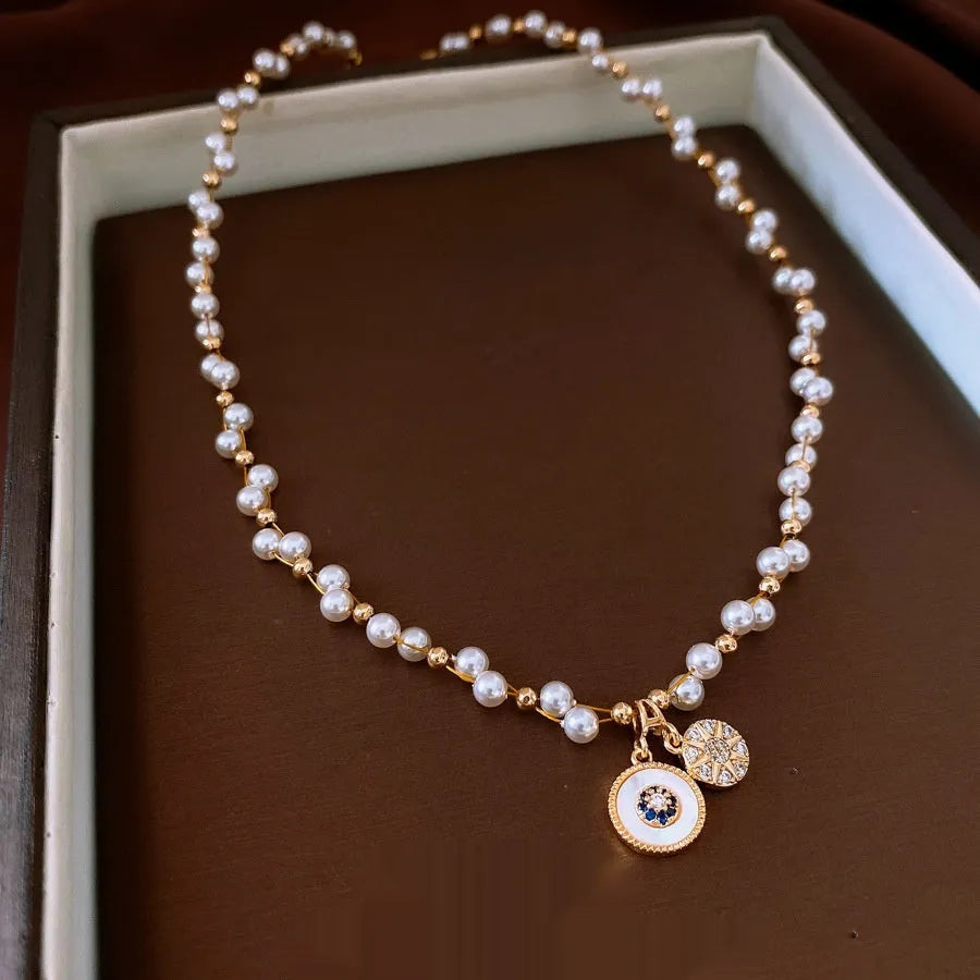 Gold electroplated necklace with round imitation pearl pendant and Chinese style geometric design