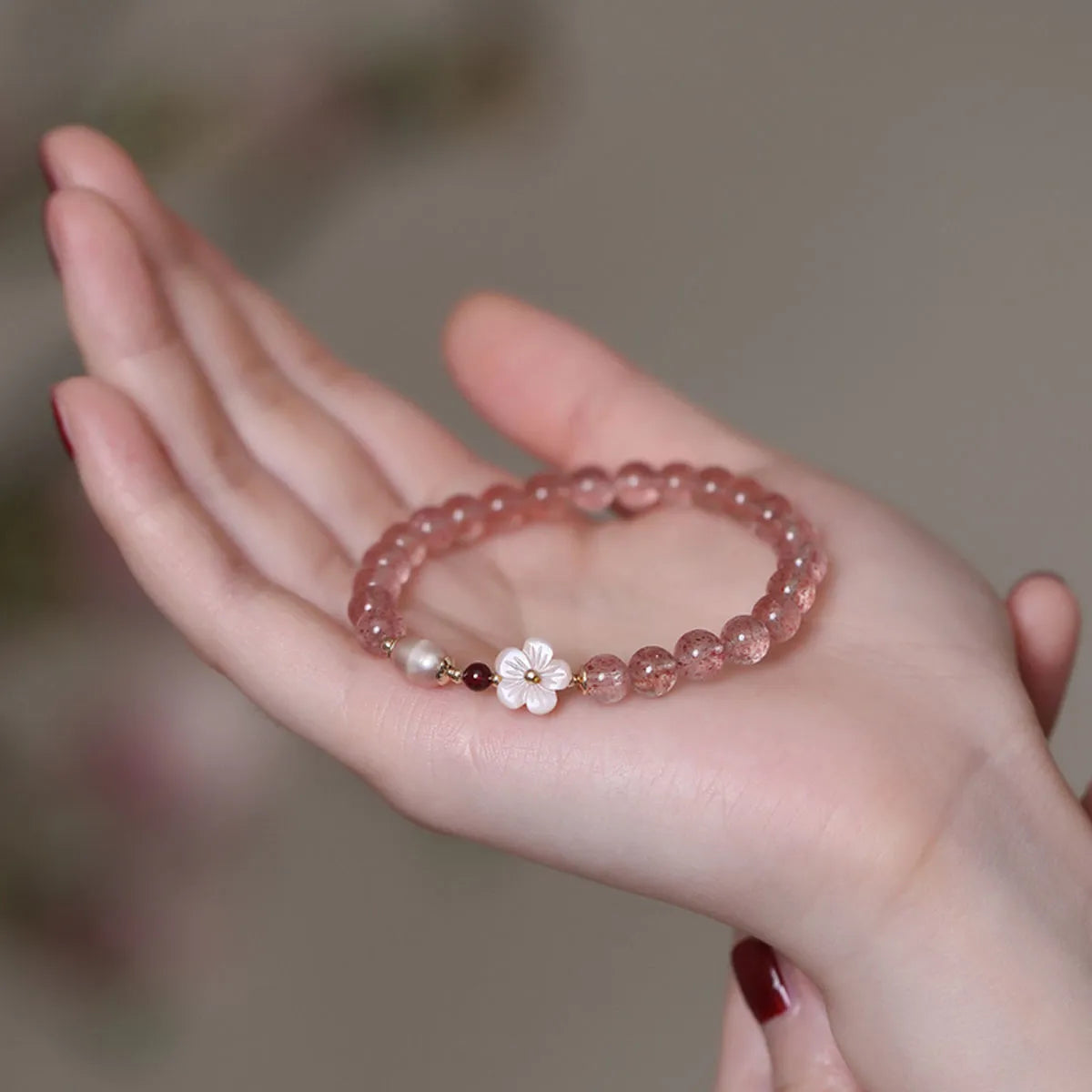 Women's strawberry quartz crystal bracelet with peach blossom flower bead design on wrist