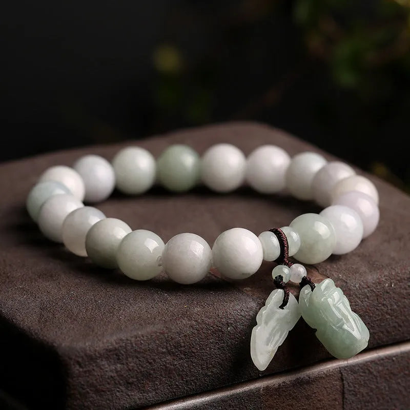 Natural green jade bracelet with a geometric shape and a hanging apple charm on a white background.