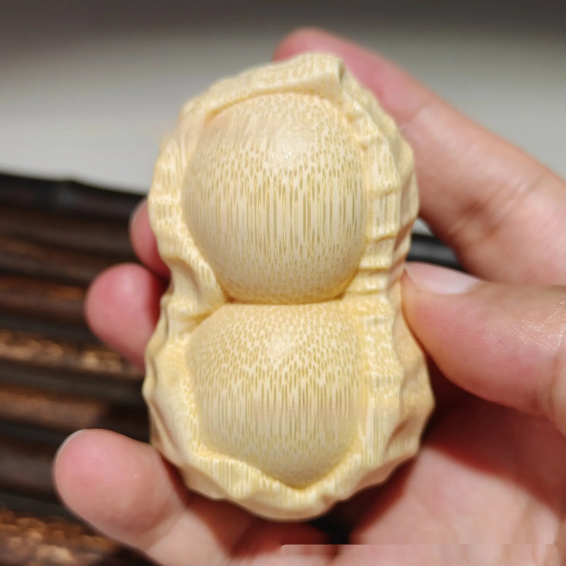 Solid natural bamboo carving of a peanut ornament on a wooden surface