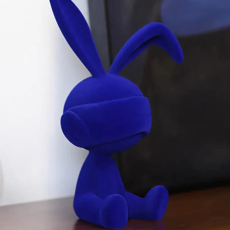 Green suede blindfold rabbit resin ornament seated on a table