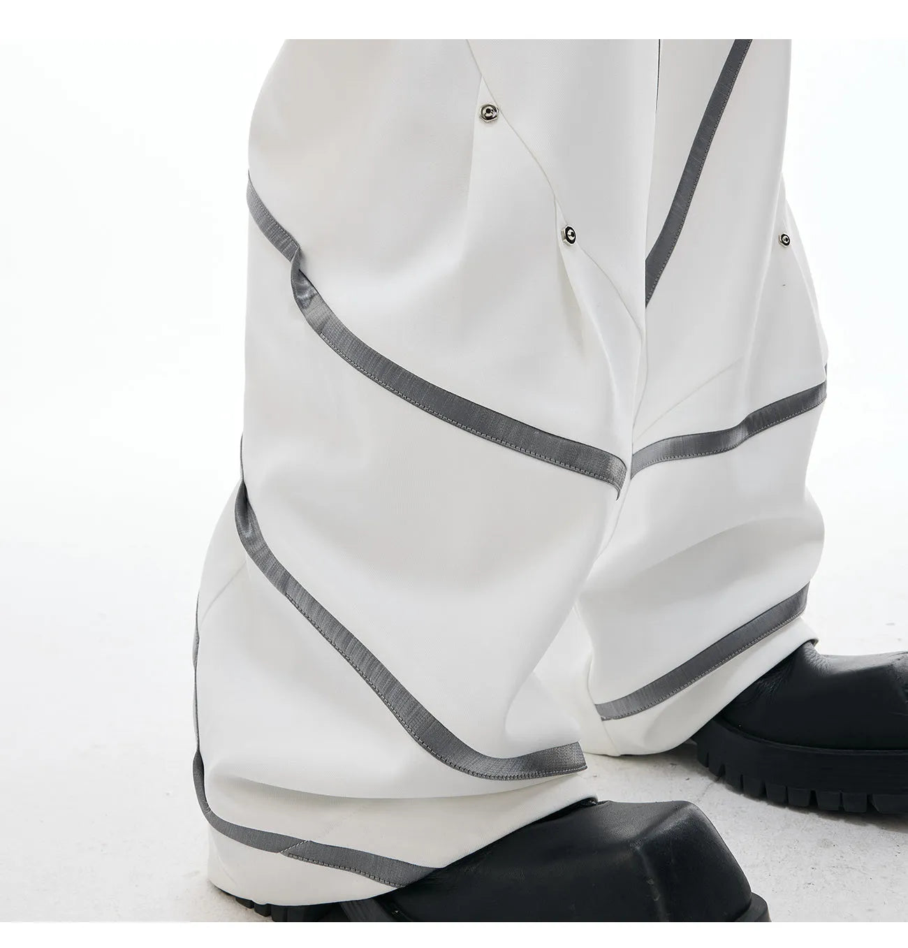 Men's black trousers with metal rivet stripes and pleated detail on the leg.